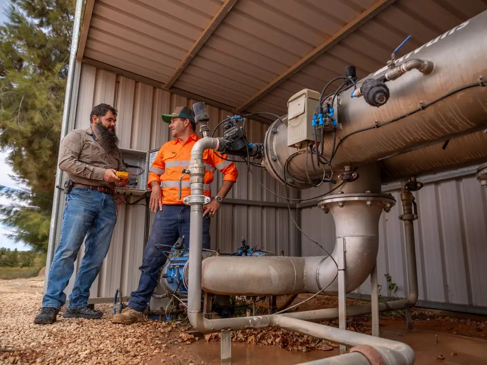 Two Ardal staff talking beside a filtration unit at a pump shed